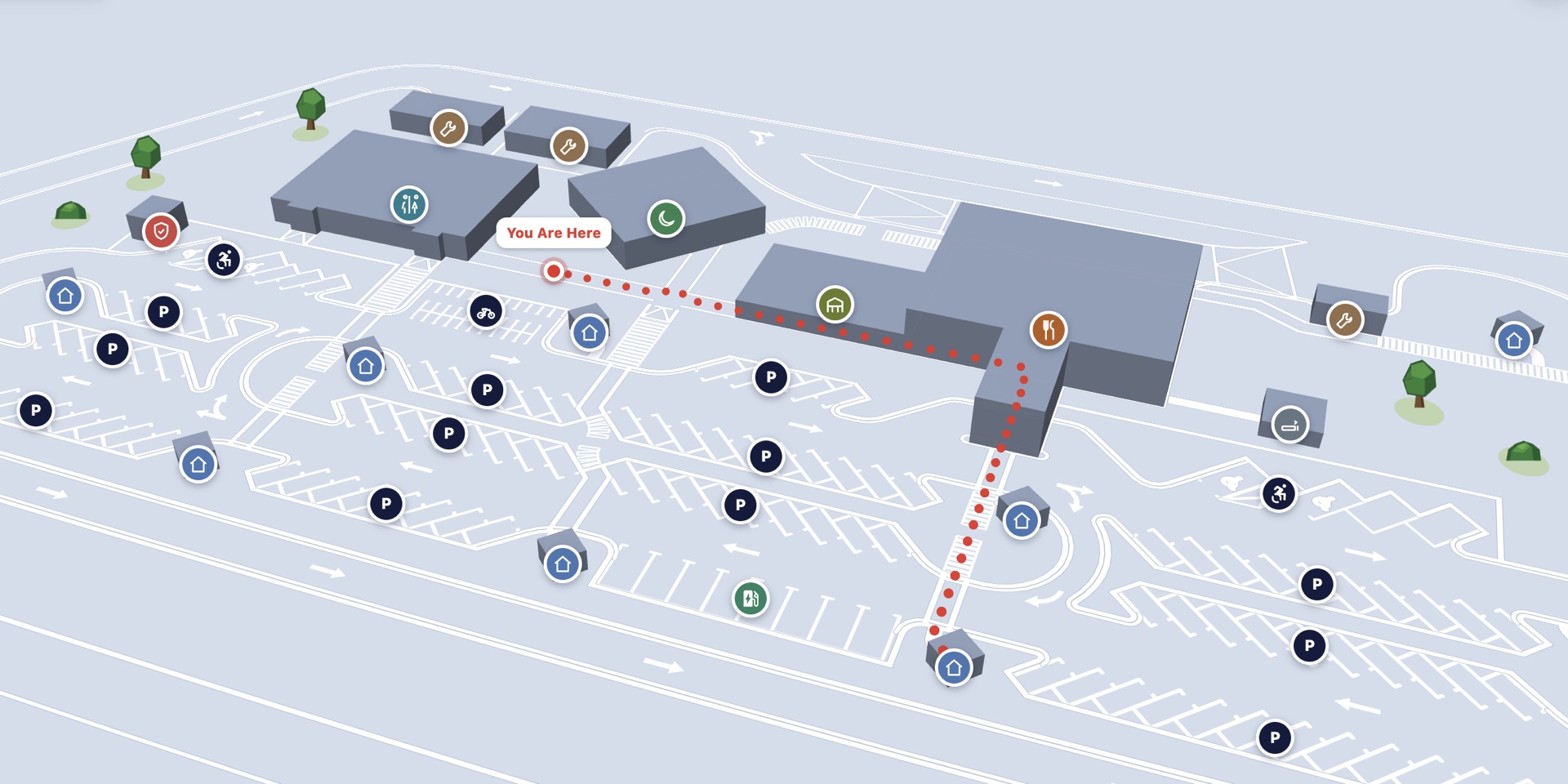 3D map viewer built by cad-to-map from a DXF site plan, showing the tool&rsquo;s own demo site rather than client work. Extruded building volumes sit above marked parking bays threaded with directional arrows and pedestrian crossings. Category pins mark parking, toilets, food, fuel, prayer facilities, accessible routes, first aid, bicycles and electric-vehicle charging. A red &ldquo;You Are Here&rdquo; marker sits beside the buildings, and a red dotted line traces the walking route from it to a destination across the site.